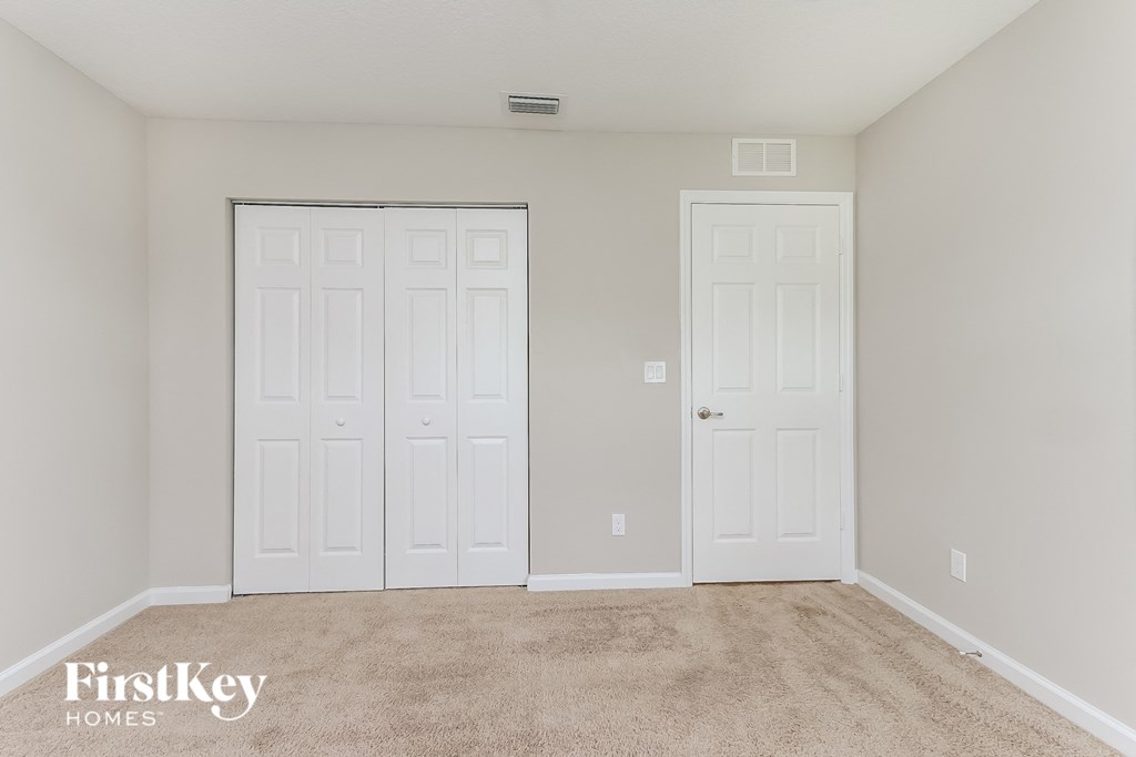 a bedroom with two white doors and a carpeted floor