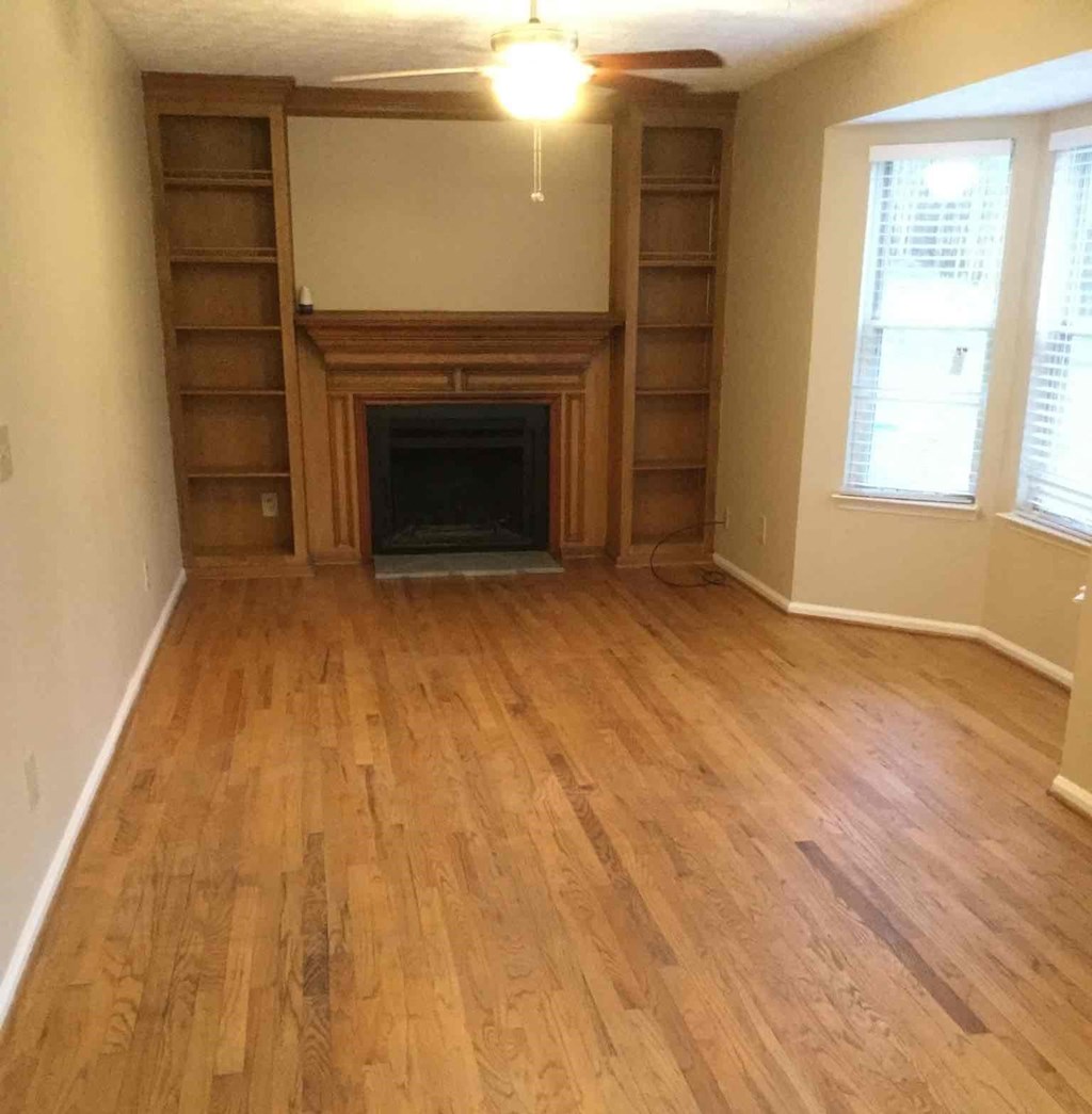A room with a fireplace and wood flooring.