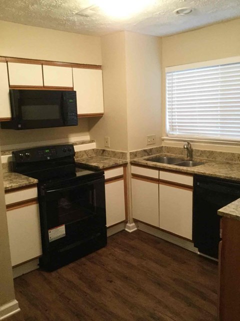 A kitchen with a black oven and white cabinets.