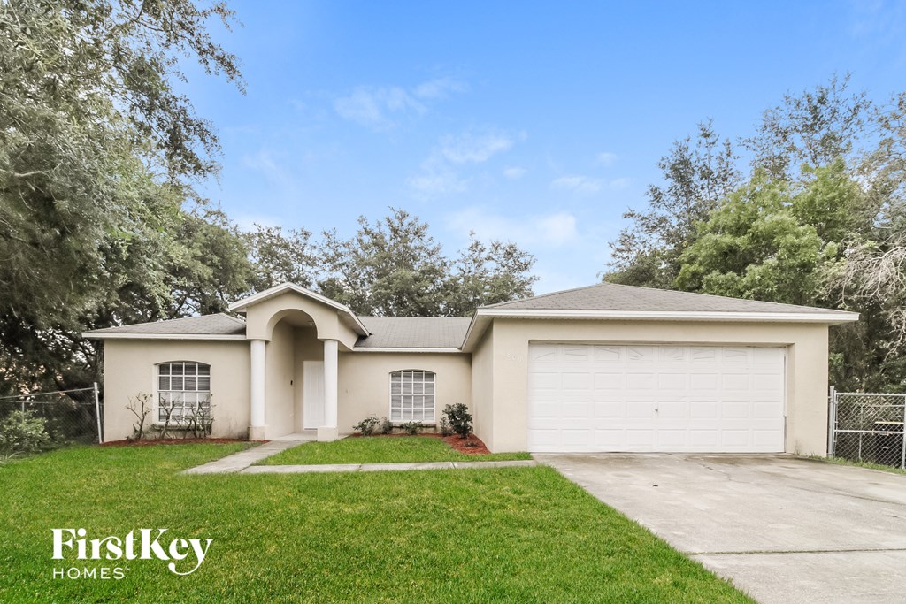 A house with a white garage door and a tree in front.