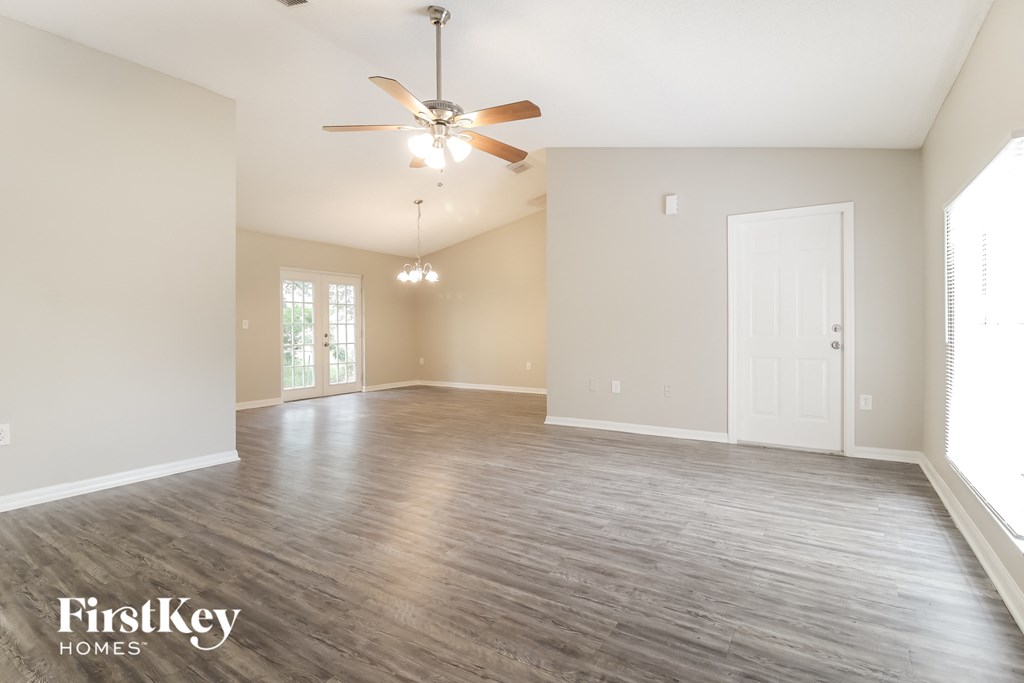 A spacious room with a ceiling fan and wooden flooring.