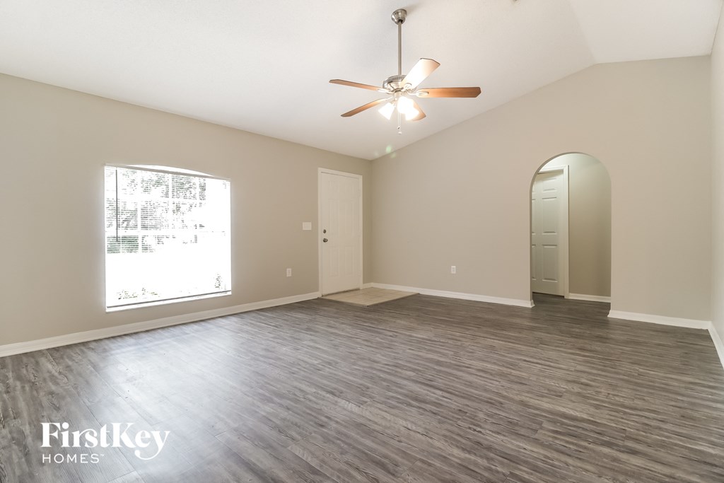 A spacious room with a ceiling fan and a large window.