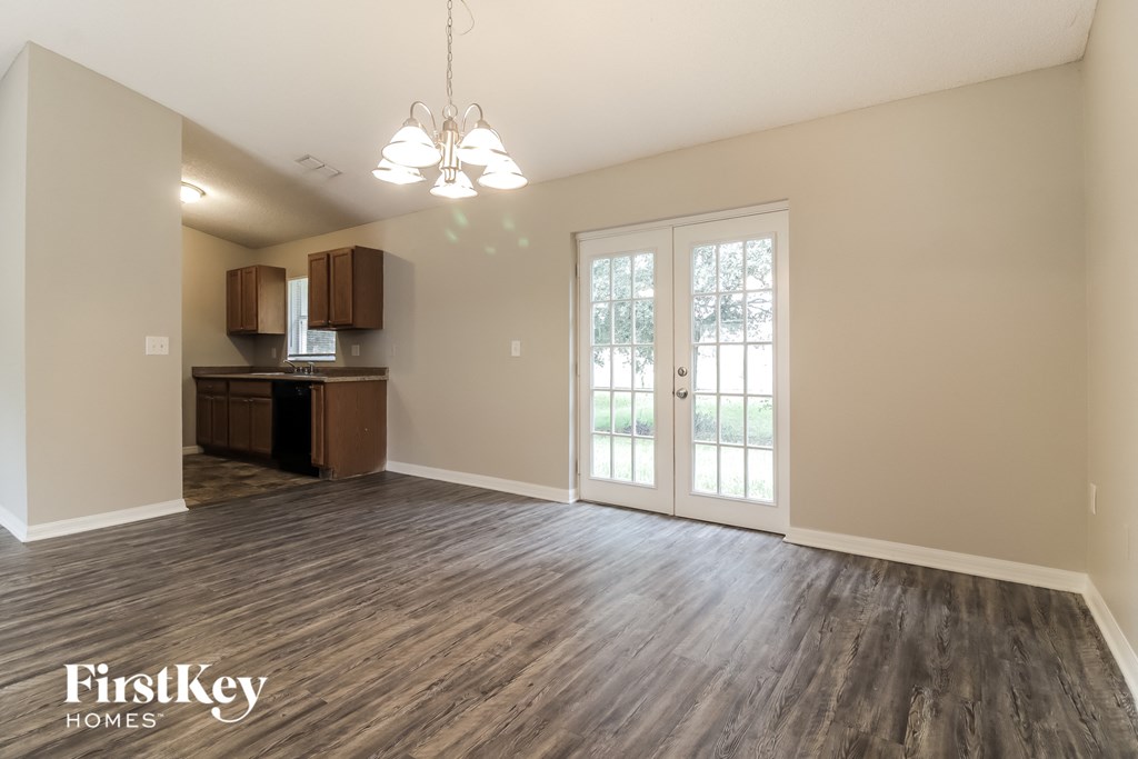 A spacious room with wooden flooring and a chandelier hanging from the ceiling.