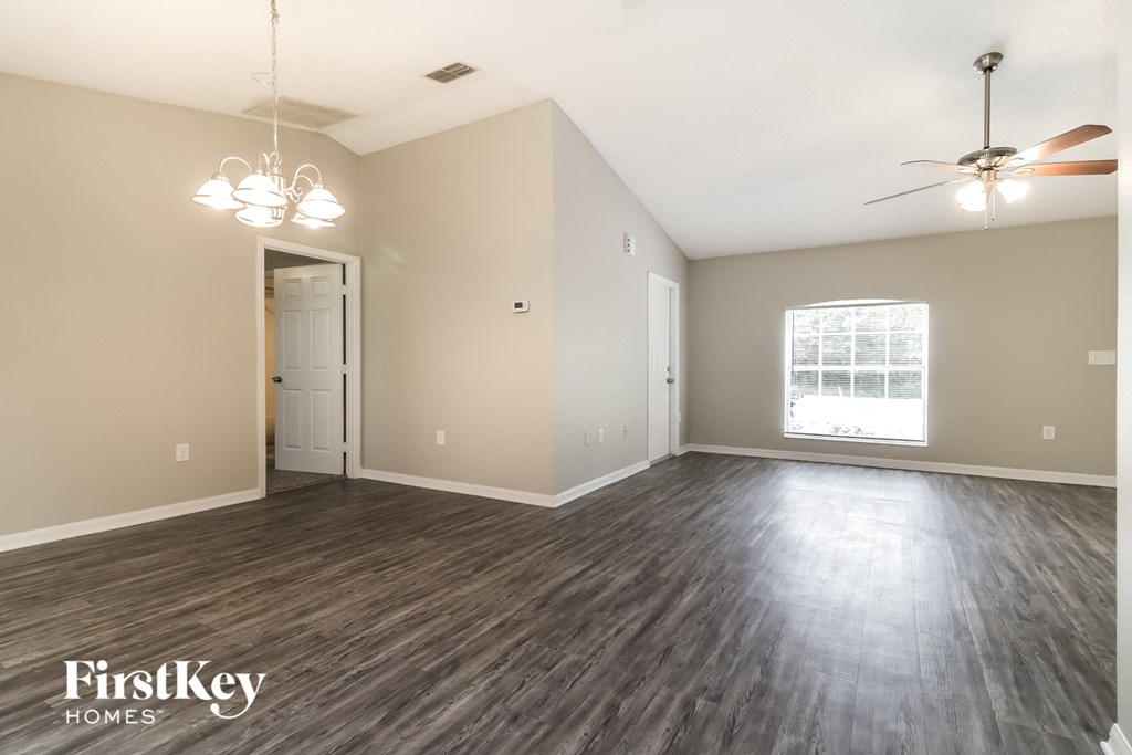 A spacious room with wooden flooring and a ceiling fan.