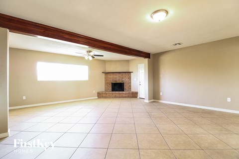 A spacious living room with a fireplace and a ceiling fan.