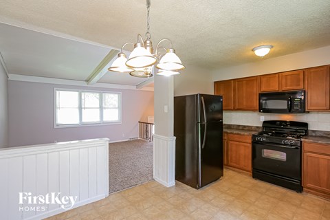 A kitchen with a black refrigerator and wooden cabinets.