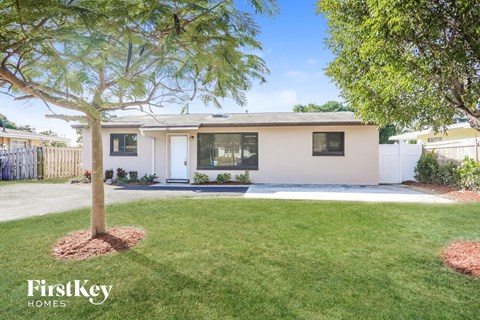 A white house with a tree in front of it.