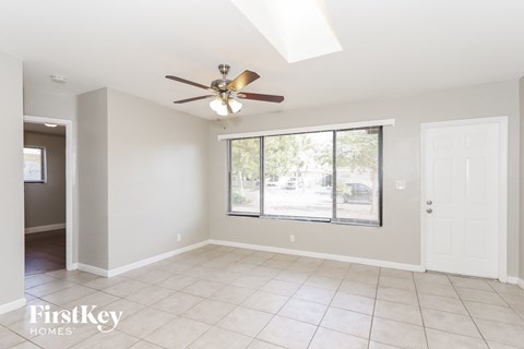 A spacious room with a ceiling fan and large windows.