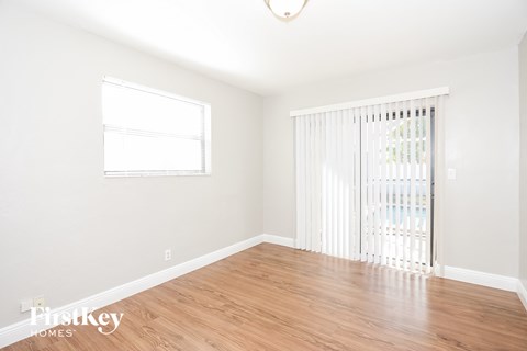 A room with wooden floors and a window with blinds.