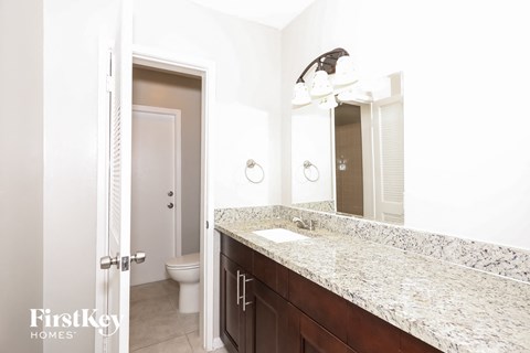 A bathroom with a marble countertop and a mirror above it.
