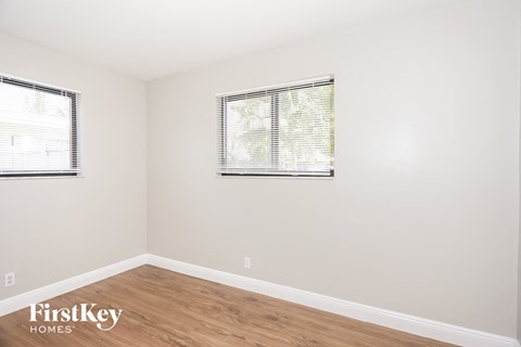 A room with wooden floors and two windows.