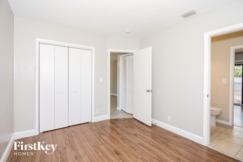 A room with white walls and wooden floors, with a FirstKey Homes logo in the bottom left corner.