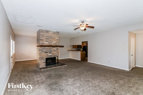 A living room with a fireplace and a ceiling fan.
