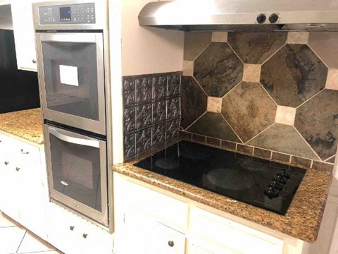 A kitchen with a double oven and a black induction cooktop.