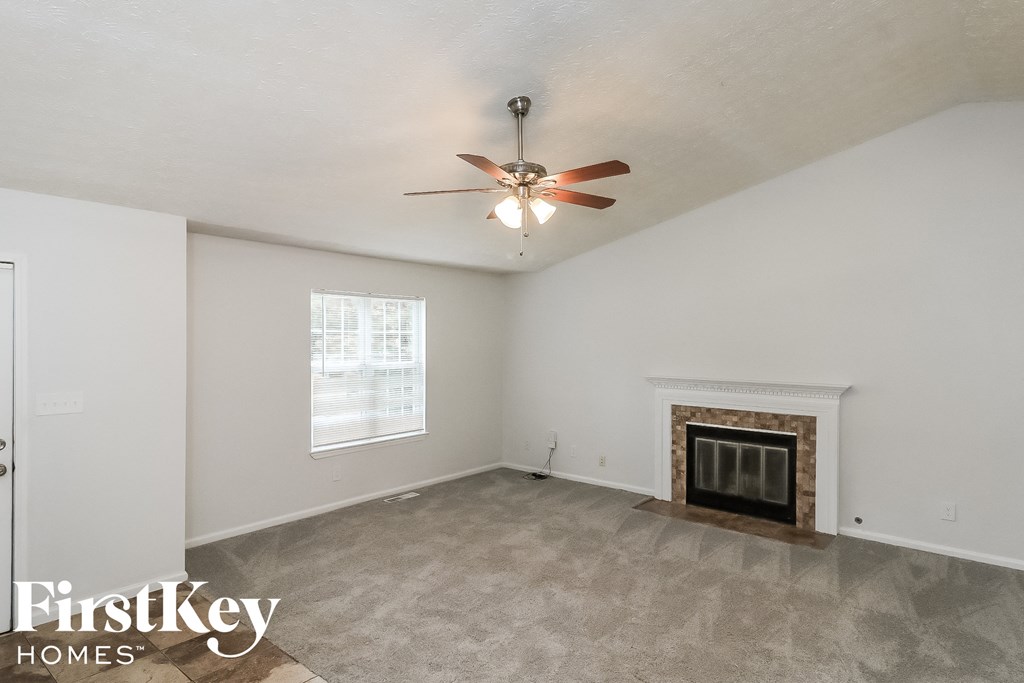A spacious living room with a fireplace and a ceiling fan.