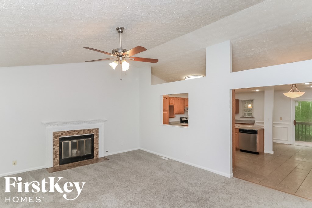 A spacious living room with a fireplace and a ceiling fan.
