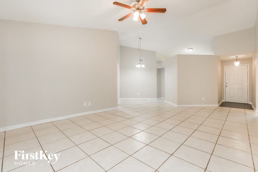 an empty living room with a ceiling fan and tiled floor