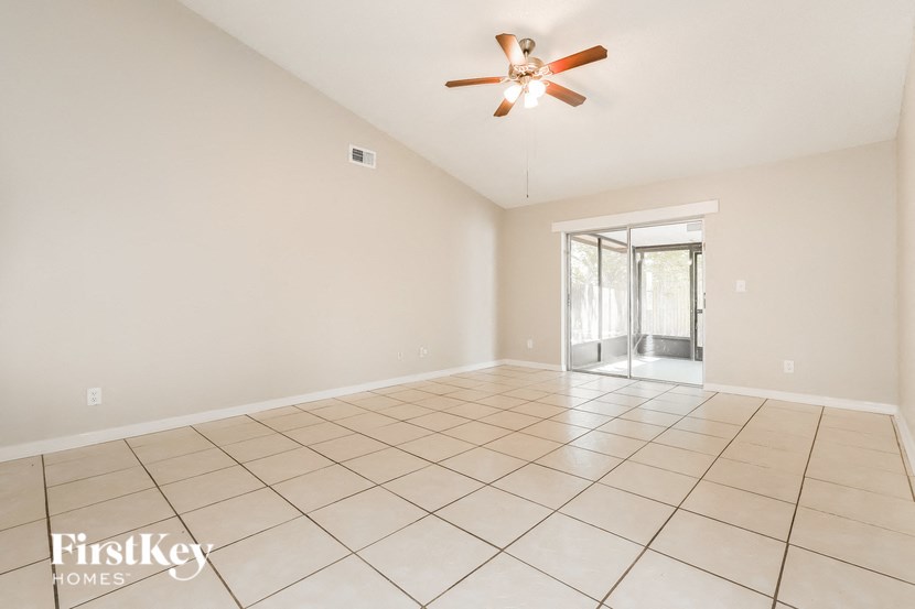 an empty living room with a ceiling fan and tiled floor
