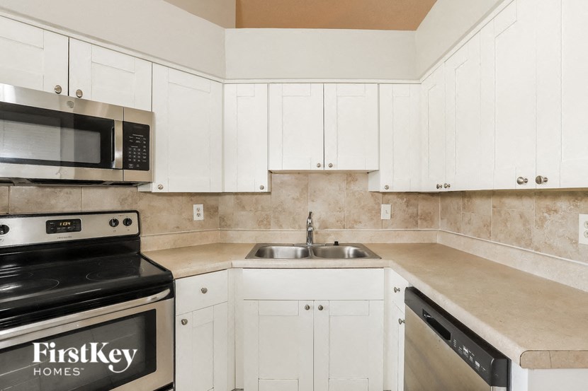 a kitchen with white cabinets and a sink and a stove