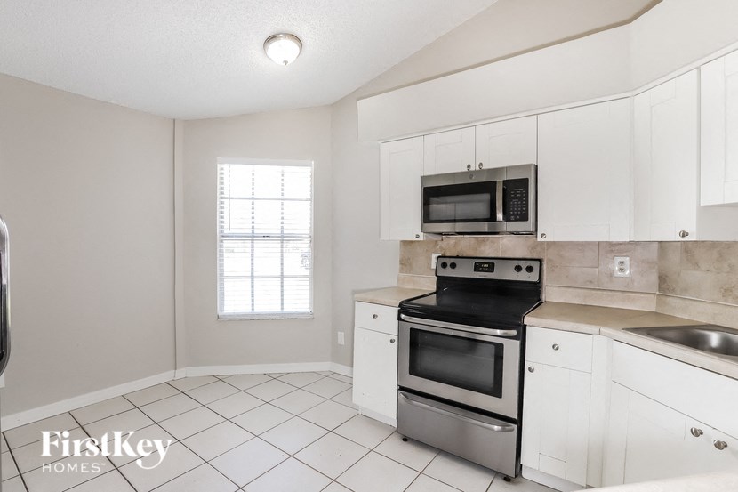 a white kitchen with stainless steel appliances and white cabinets