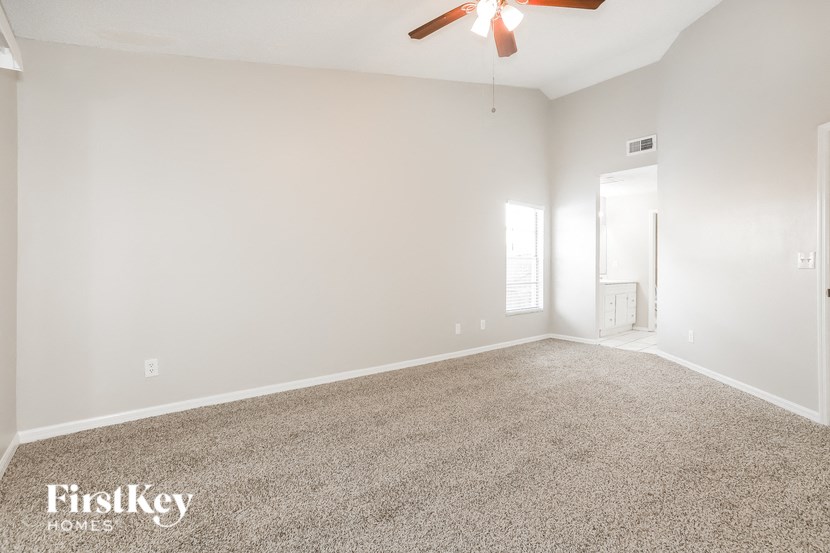an empty living room with a ceiling fan