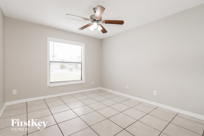an empty living room with a ceiling fan and tiled floor