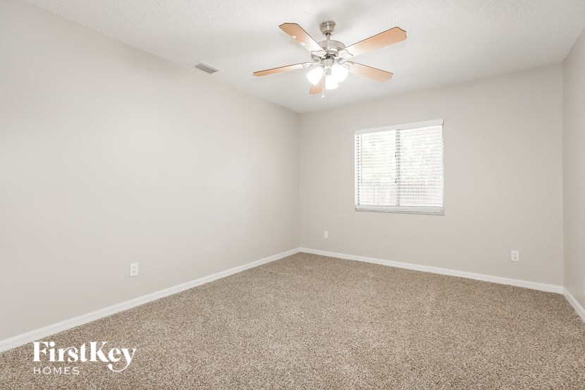 an empty room with a ceiling fan and a window