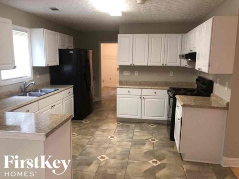 A kitchen with black appliances and white cabinets.