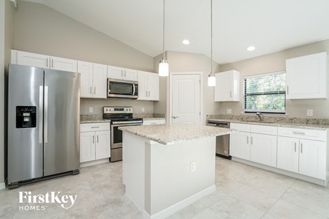 a large kitchen with white cabinets and stainless steel appliances