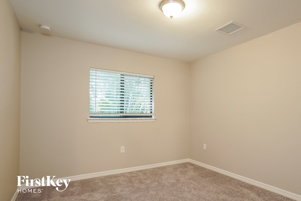 a bedroom with a window and a carpeted floor