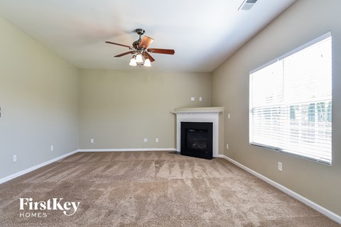 an empty living room with a fireplace and a ceiling fan