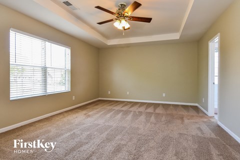 an empty living room with a ceiling fan and a large window