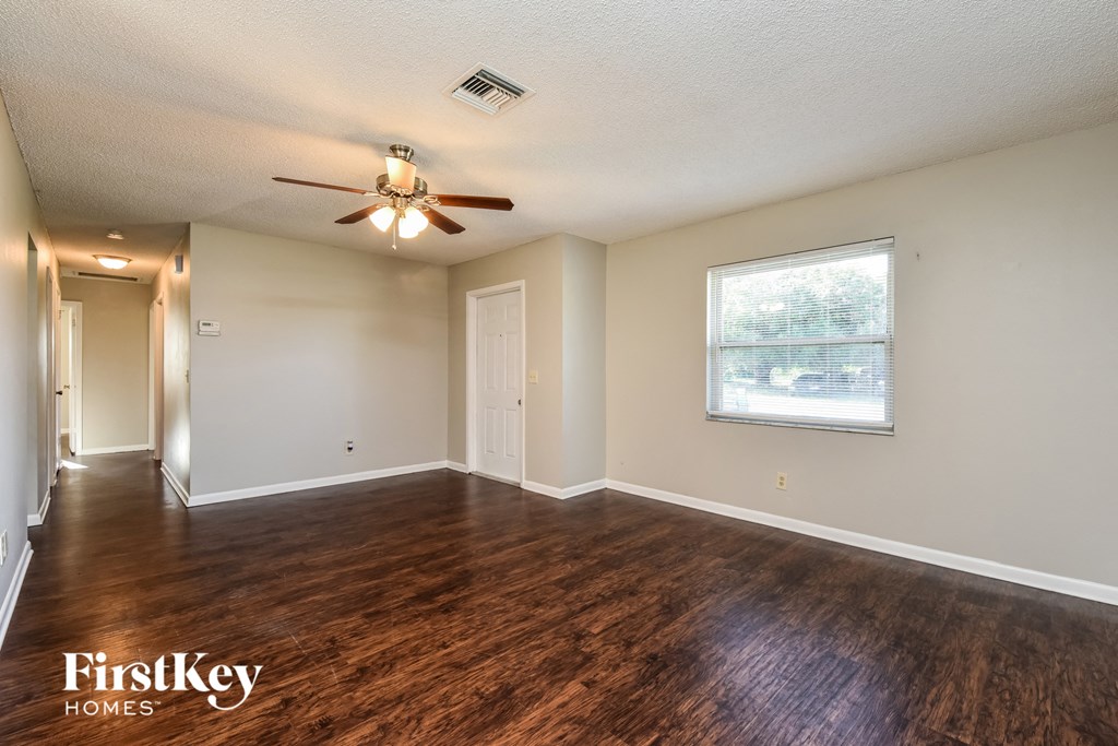 A spacious room with a ceiling fan and wooden flooring.