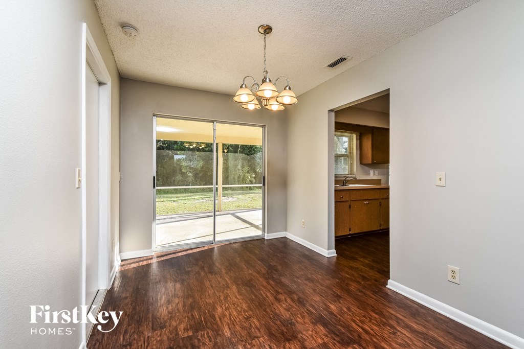 A room with wooden floors and a chandelier hanging from the ceiling.