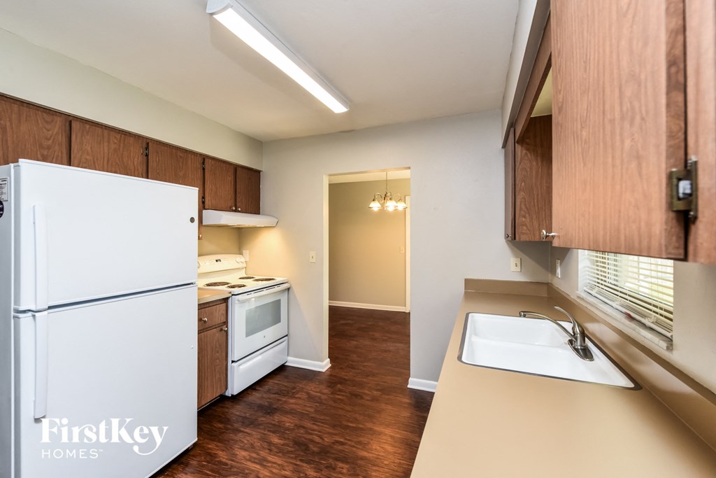 A kitchen with a white refrigerator and wooden cabinets.