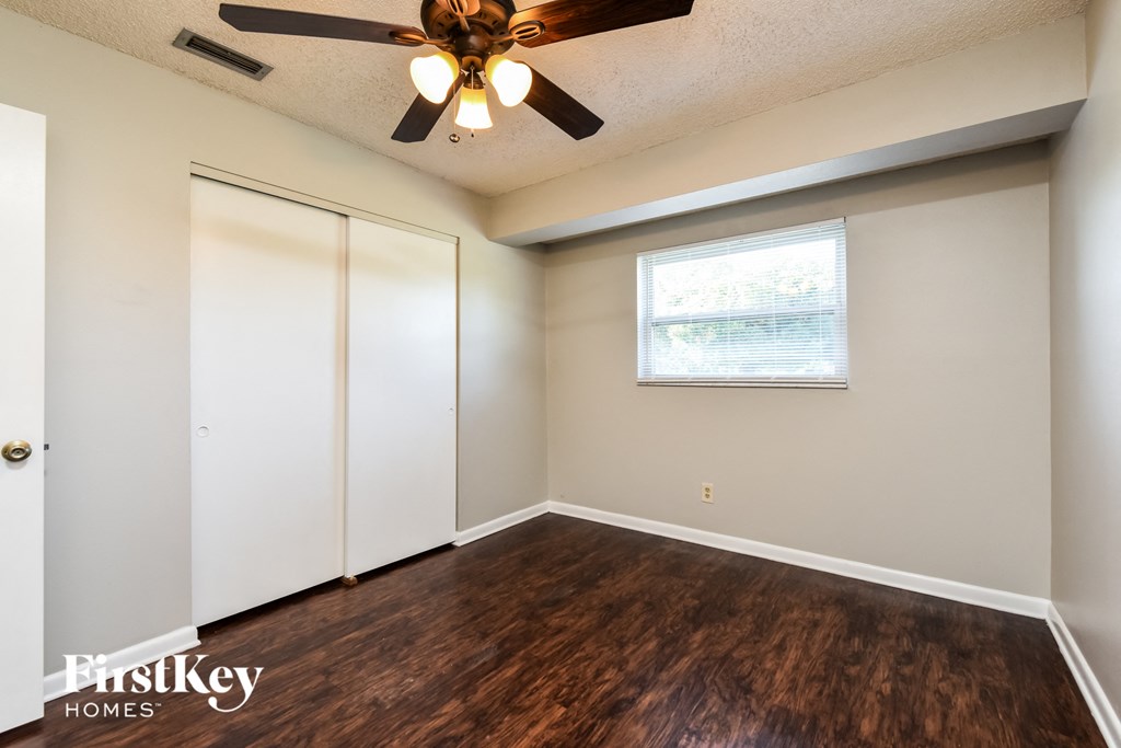 A room with a ceiling fan and a window with blinds.