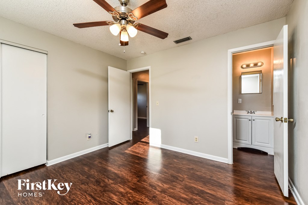 A room with a ceiling fan and wooden floors.