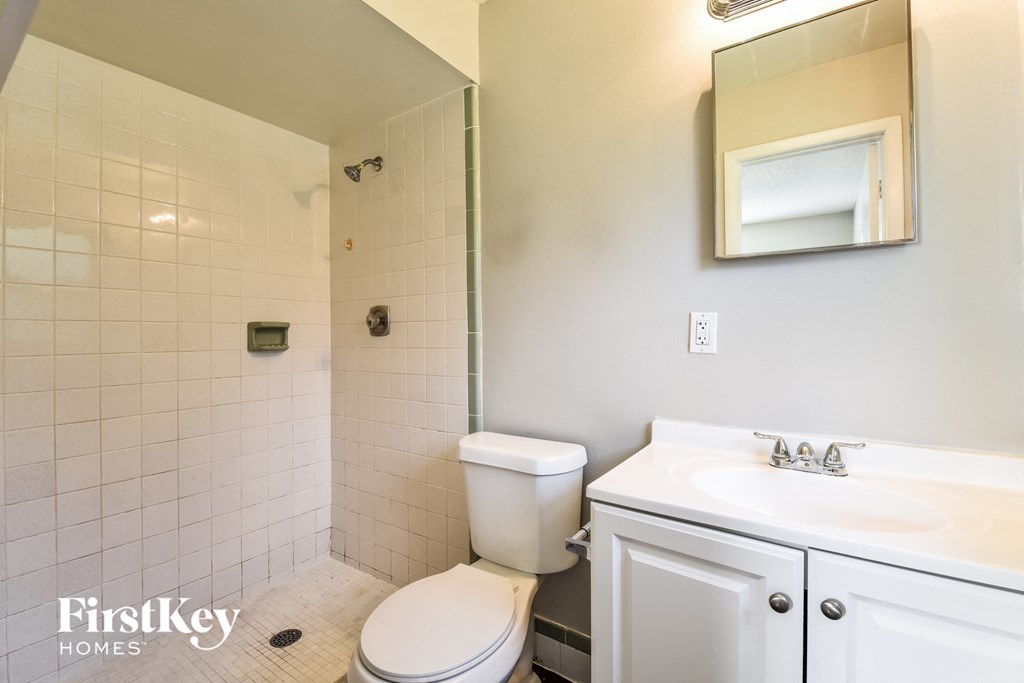 A white toilet in a bathroom with a white sink and a mirror.