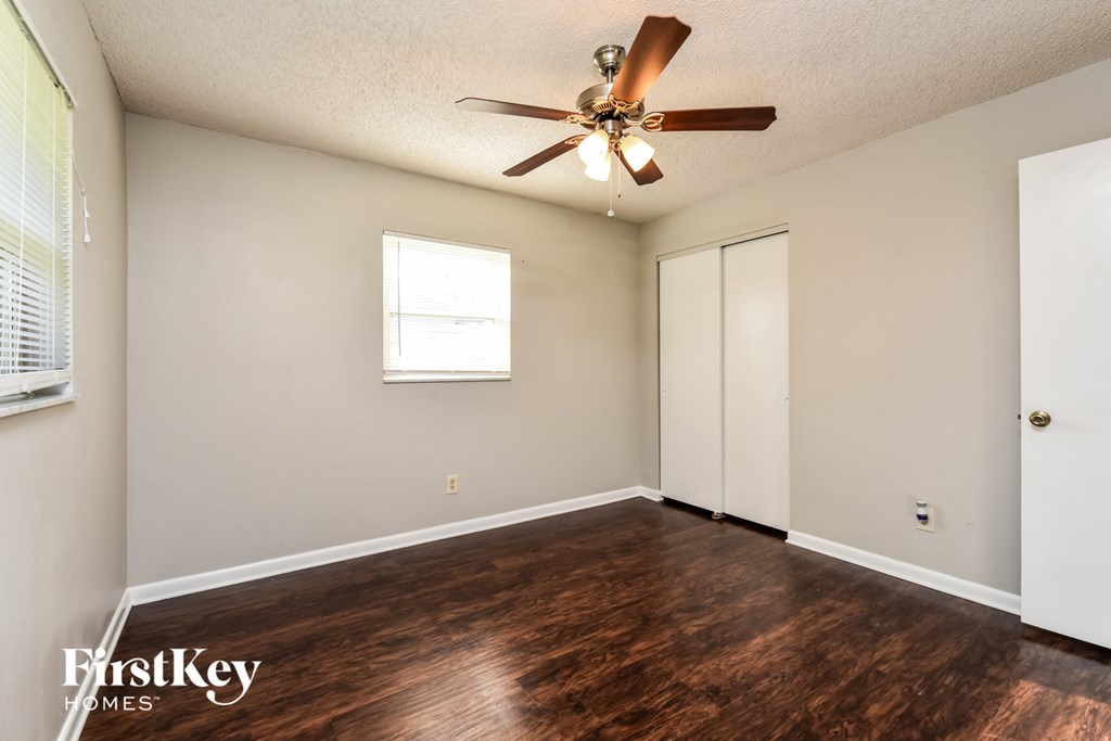 A room with a ceiling fan and wooden flooring.
