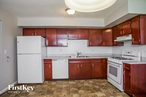 an empty kitchen with white appliances and wooden cabinets