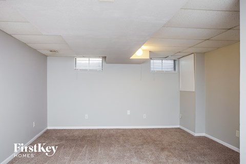 the living room of an apartment with carpet and white walls
