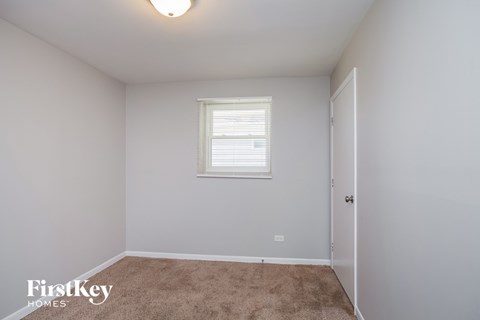 a bedroom with white walls and carpet and a window