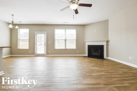an empty living room with a fireplace and a ceiling fan