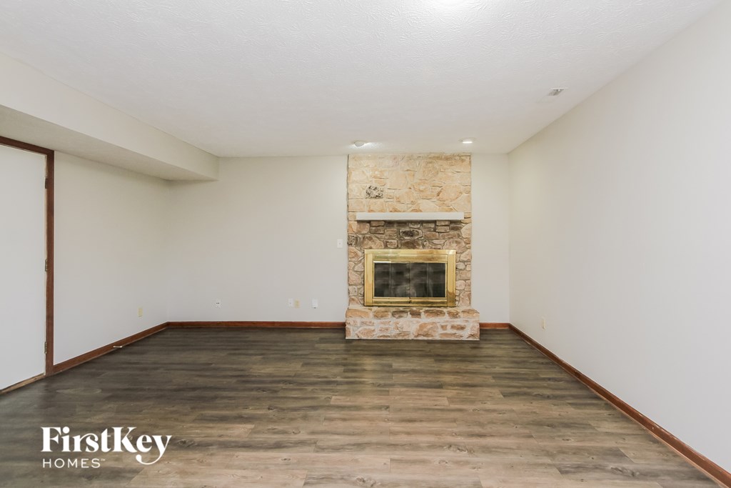 A room with a stone fireplace and wooden flooring.