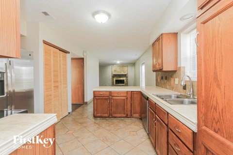 A kitchen with wooden cabinets and a tiled floor.