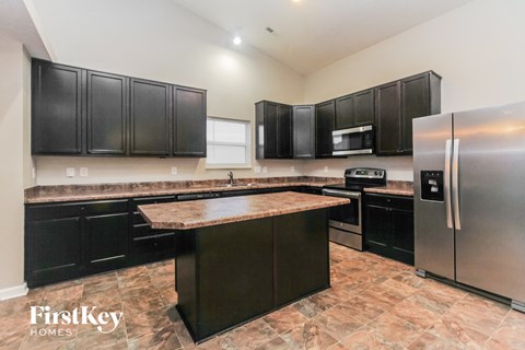 a large kitchen with black cabinets and stainless steel appliances
