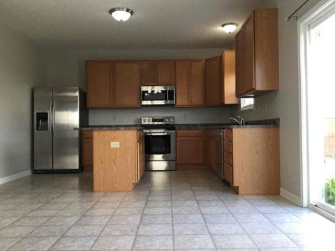 an empty kitchen with stainless steel appliances and wooden cabinets