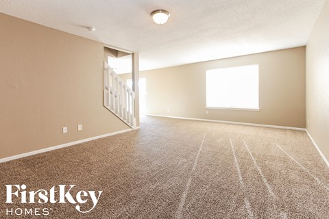 A spacious room with a carpeted floor and a window letting in natural light.