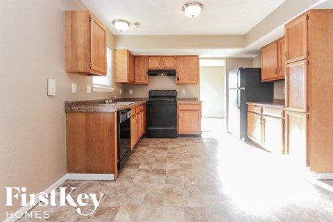 A kitchen with wooden cabinets and a black refrigerator.
