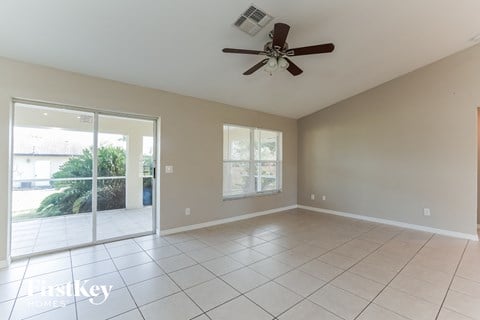 an empty living room with a ceiling fan and a sliding glass door